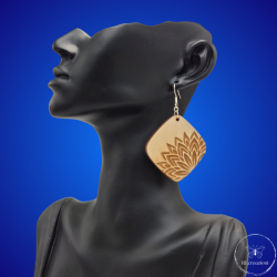 une paire de boucles d'oreilles en bois gravées au laser, avec un crochet en argent et un motif décoratif en métal. Très légères