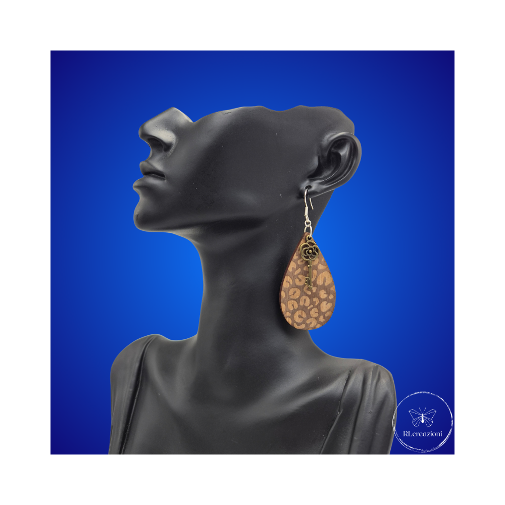 une paire de boucles d'oreilles en bois gravées au laser, avec un crochet en argent et un motif décoratif en métal. Très légères