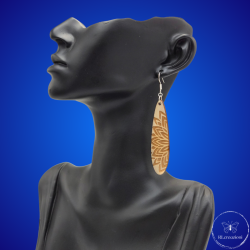 une paire de boucles d'oreilles en bois gravées au laser, avec un crochet en argent et un motif décoratif en métal. Très légères