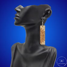une paire de boucles d'oreilles en bois gravées au laser, avec un crochet en argent et un motif décoratif en métal. Très légères