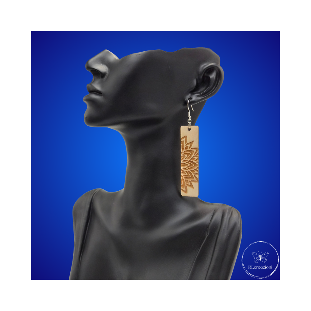 une paire de boucles d'oreilles en bois gravées au laser, avec un crochet en argent et un motif décoratif en métal. Très légères