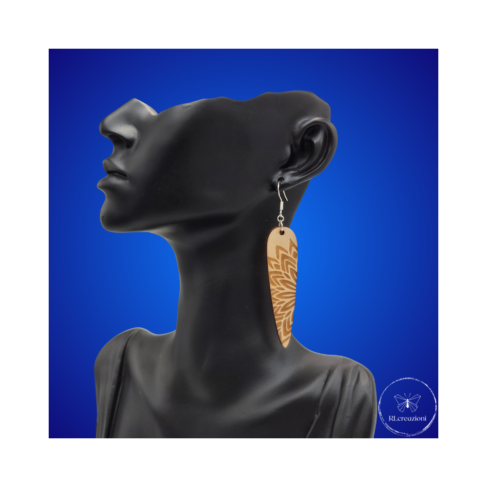 une paire de boucles d'oreilles en bois gravées au laser, avec un crochet en argent et un motif décoratif en métal. Très légères